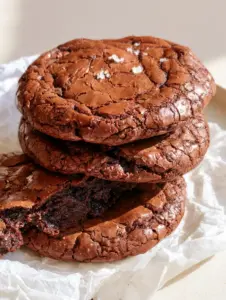 Close up of a Fudgy Brownie Cookie broken open to reveal a dense and moist chocolate interior.