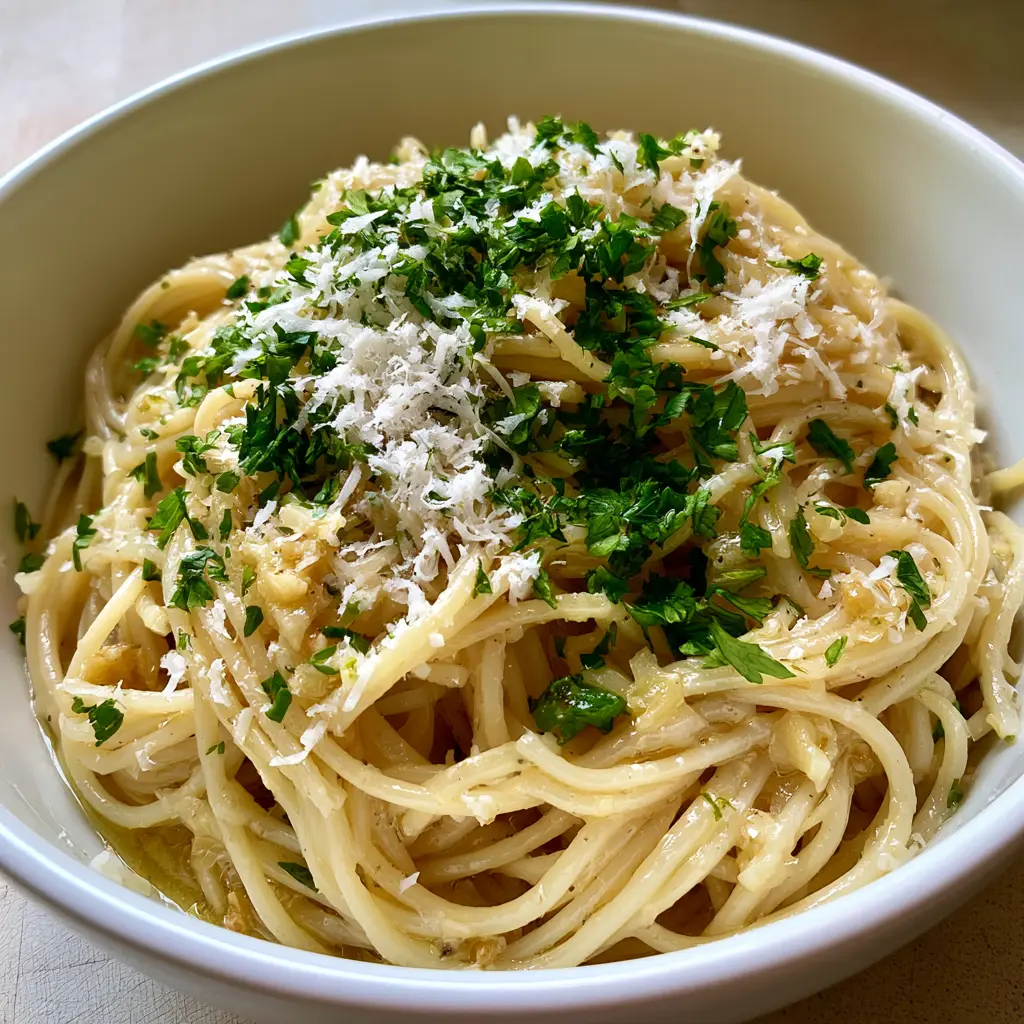 Garlic Butter Pasta: The Ultimate 15-Minute Dinner Recipe 1 Close-up view of spaghetti noodles coated in a translucent golden garlic butter sauce on a wooden surface.