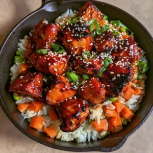 Close-up of glazed One-Pan Honey BBQ Chicken pieces showing charred edges and sesame seeds garnish.