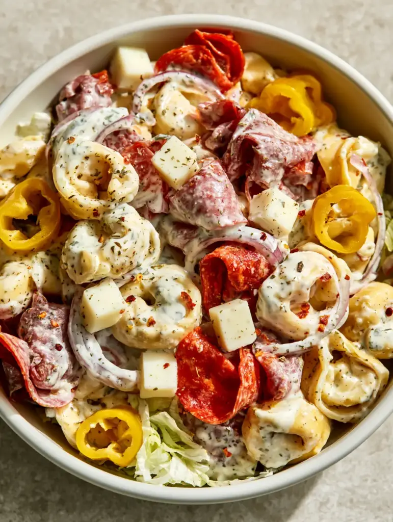 Top-down view of Italian Grinder Tortellini Salad with cheese tortellini, salami, pepperoni, and provolone in a thick creamy herb dressing.